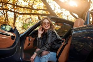 Sexy young woman in jeans smiling in a cabriolet