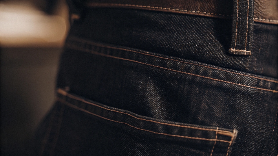 A detailed close-up shot of the signature 'Lazy S' stitching on the back pocket of a Lee jean.