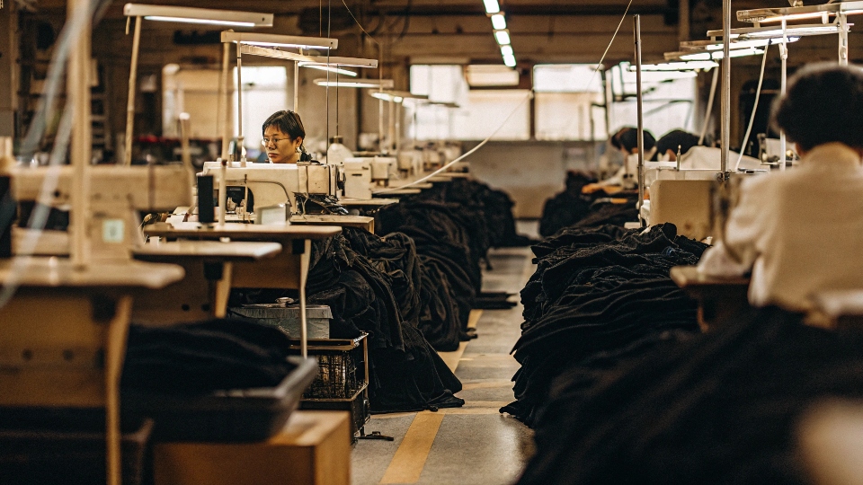 An inside look at a modern denim factory, showing workers at sewing stations.