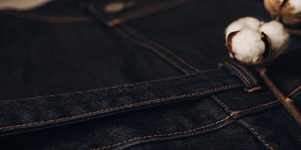 A close-up shot showing the texture of pure cotton denim next to a fluffy cotton boll, emphasizing the connection.
