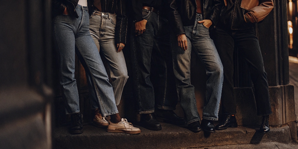 A group of young, stylish people on a city street, all wearing different types of loose-fitting blue jeans.