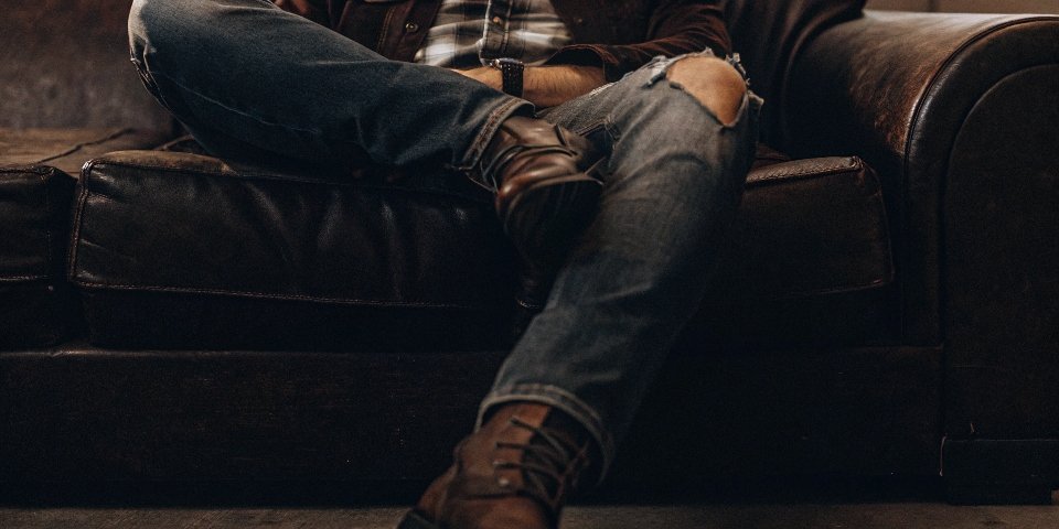 A close-up shot of a man comfortably sitting in a broken-in pair of jeans, looking relaxed and confident.