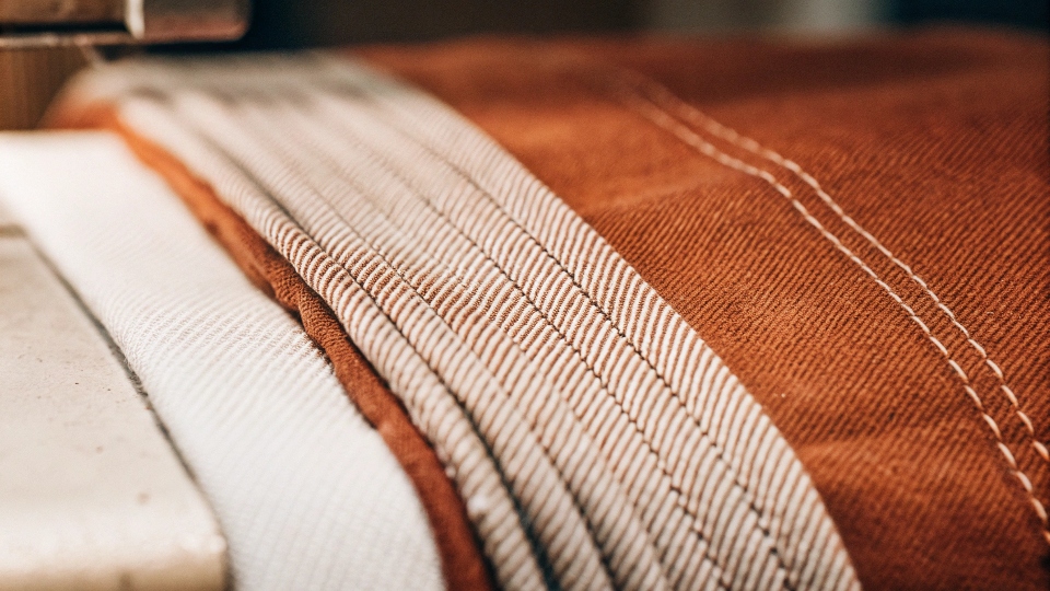 A macro photograph of denim fabric showing the distinct diagonal twill weave and the blue and white threads.