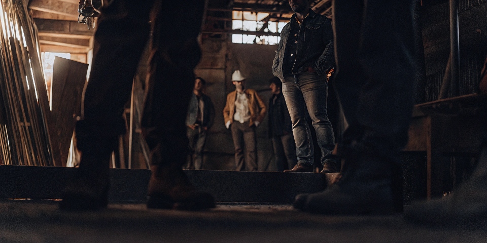 A powerful montage of diverse people wearing jeans: a construction worker, a rock star on stage, a CEO at a casual meeting, and a model on a runway.