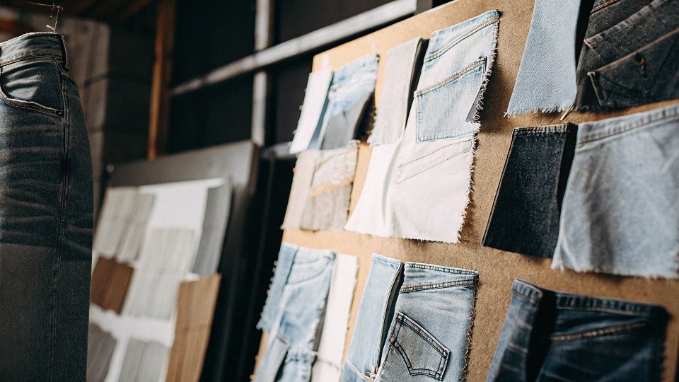A designer's mood board covered in denim swatches showing different washes, textures, and distressing techniques.