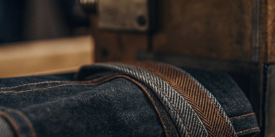 A macro, close-up shot of the diagonal weave of a piece of raw denim fabric.