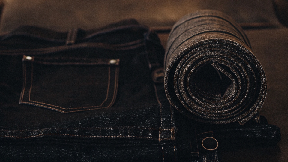 A visual diagram showing the relationship: a roll of denim fabric, a pair of jeans, and the Levi's brand logo.