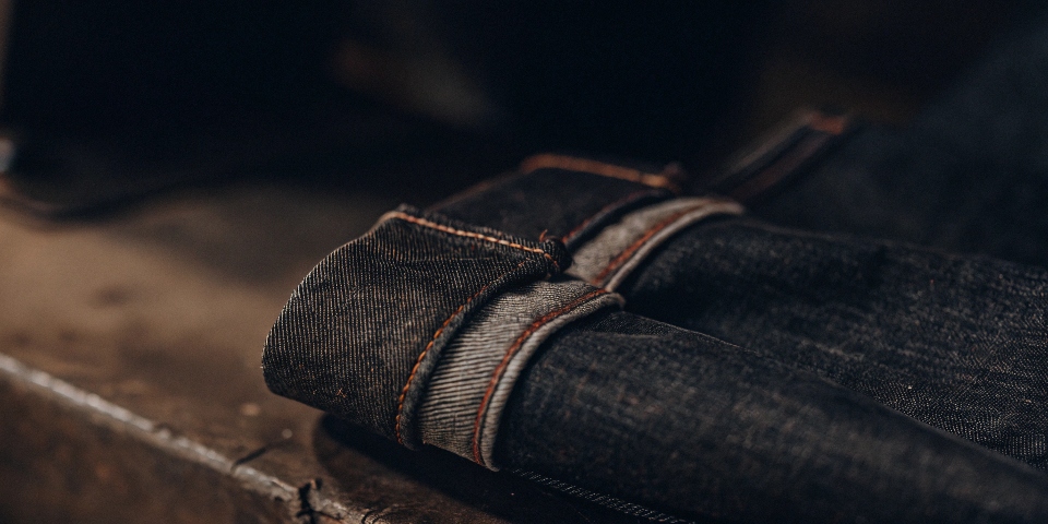 A close-up shot of the iconic red-line selvedge ID on the upturned cuff of a dark pair of jeans.