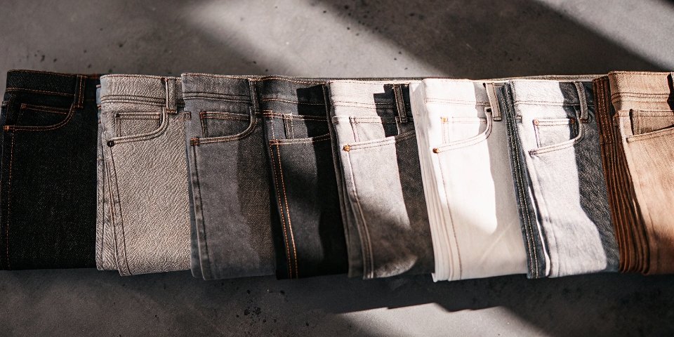 A collection of denim swatches in various shades and textures, including rigid 100% cotton, stretch denim, and soft Tencel blends.