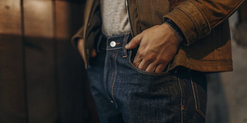 A close-up shot of a person flipping over the cuff of their jeans to reveal the lighter interior fabric.