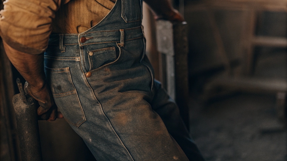 An old, black-and-white photograph of a 19th-century miner wearing rugged denim, highlighting the durability needed.