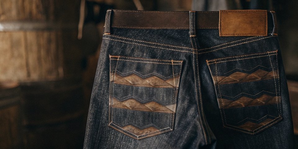 A close-up shot of beautiful, high-contrast honeycomb fades on the back of a well-worn pair of raw denim jeans.