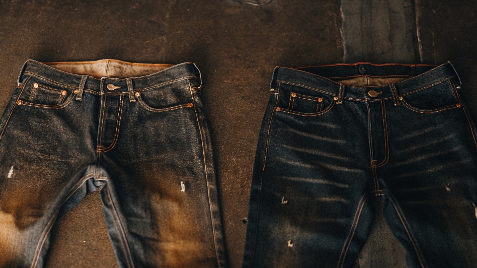 A pair of stretch jeans looking saggy and warped after being improperly machine dried, with warning icons for heat.