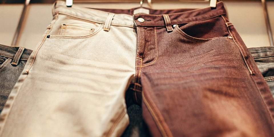 A close-up shot of the rich, deep indigo color of a pair of raw, unwashed denim jeans.
