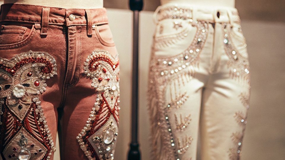 A pair of heavily embellished Gucci jeans with intricate embroidery and crystals on a mannequin.