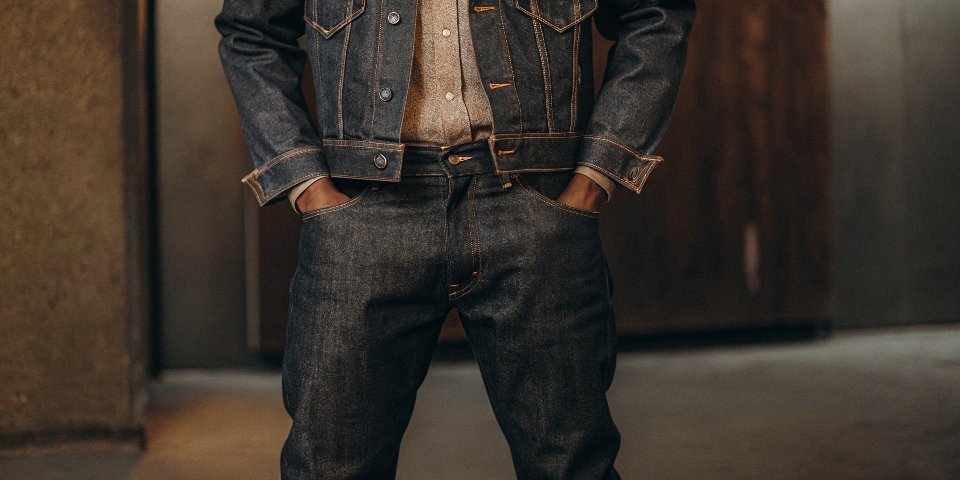 A person wearing a light-wash denim jacket with dark, raw denim jeans, showing clear contrast.