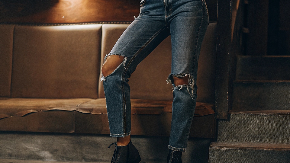 A fashion-forward person wearing subtly distressed denim in a modern, relaxed fit.