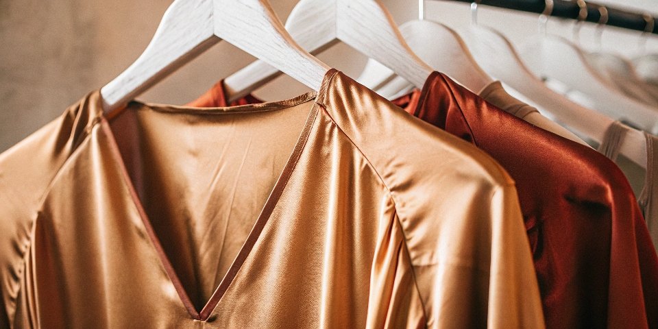 A minimalist photo of a chic silk blouse hanging elegantly on a simple rack.