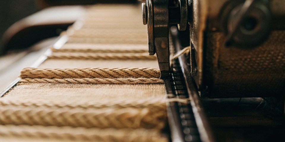 A macro close-up image showing the diagonal twill weave of stretch denim, with the individual cotton and elastic fibers visible.