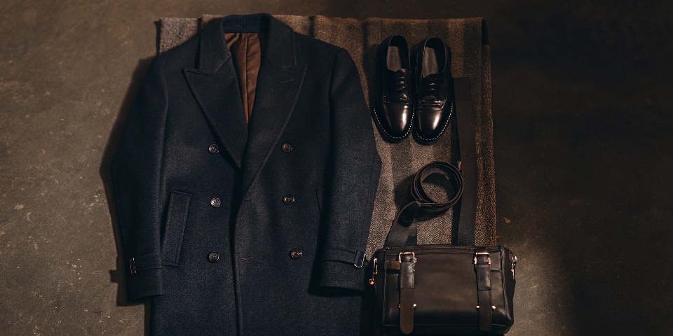 A classic, elegant outfit featuring a navy blue wool coat paired with black trousers and black shoes.