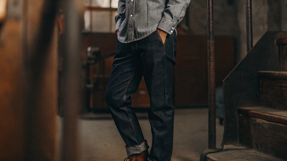 A stylish person wearing a light wash chambray shirt with dark navy blue jeans, demonstrating the principle of contrast.