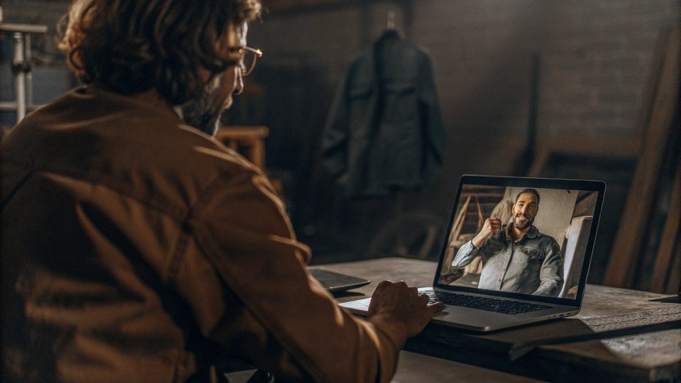 A designer on a video call with a factory manager, discussing a detailed jean sample.