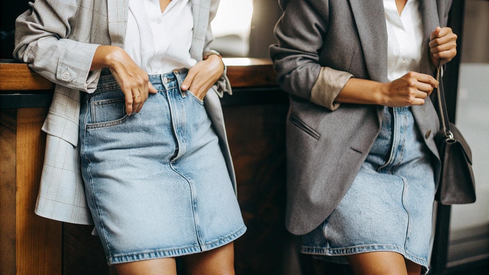 A stylish woman over 40 wearing a knee-length A-line denim skirt with a blazer.