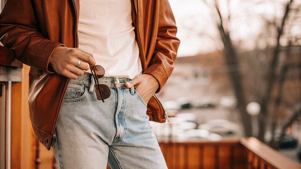 A stylish man wearing baggy jeans with a well-fitted black leather jacket and a white t-shirt.