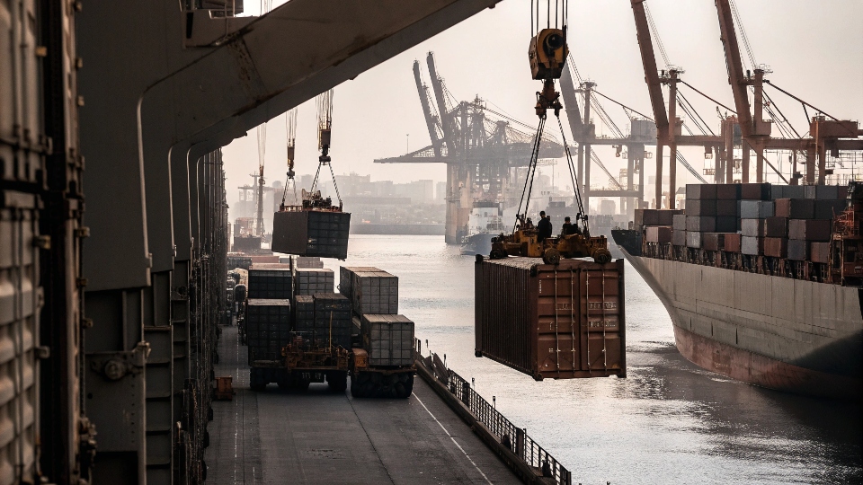 Shipping containers being loaded onto a cargo ship at a busy Chinese port.
