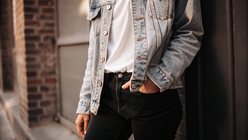 A person looking stylish in a blue denim jacket paired with black jeans and a white t-shirt.