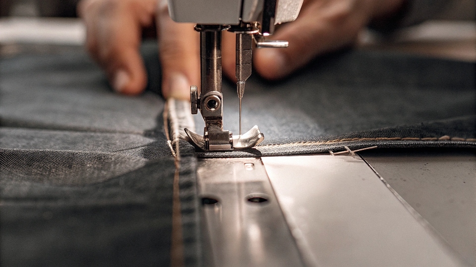 A close-up diagram showing how a tailor sews a strip of denim into the outseam of a jean leg.