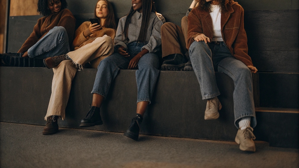 A diverse group of young people (Gen Z) hanging out, all wearing different styles of baggy jeans comfortably.