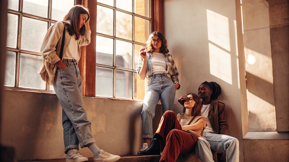 A diverse group of Gen Z friends hanging out, all wearing different styles of baggy jeans.