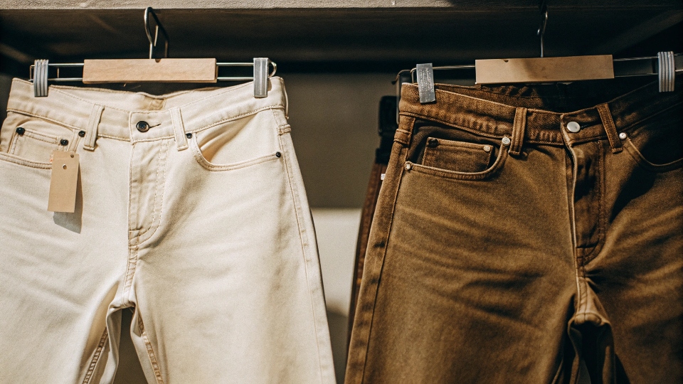Two pairs of jeans, one 100% cotton and one stretch denim, with tags indicating their fabric content.