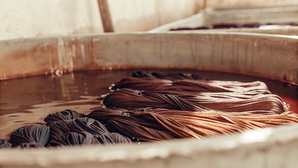 A collection of various black cotton clothing items soaking in a large pot.