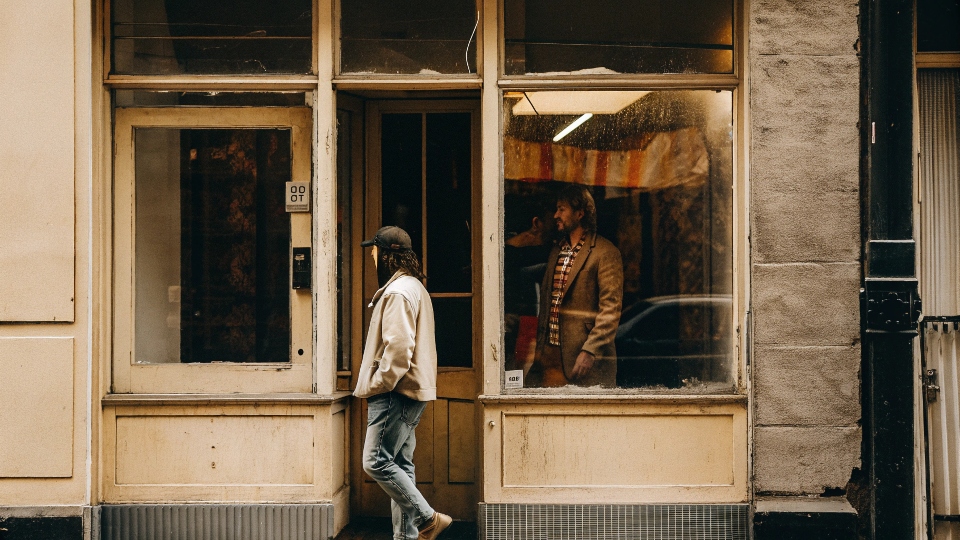A faded photograph of a storefront from the early 2000s with an Earl Jeans advertisement in the window.