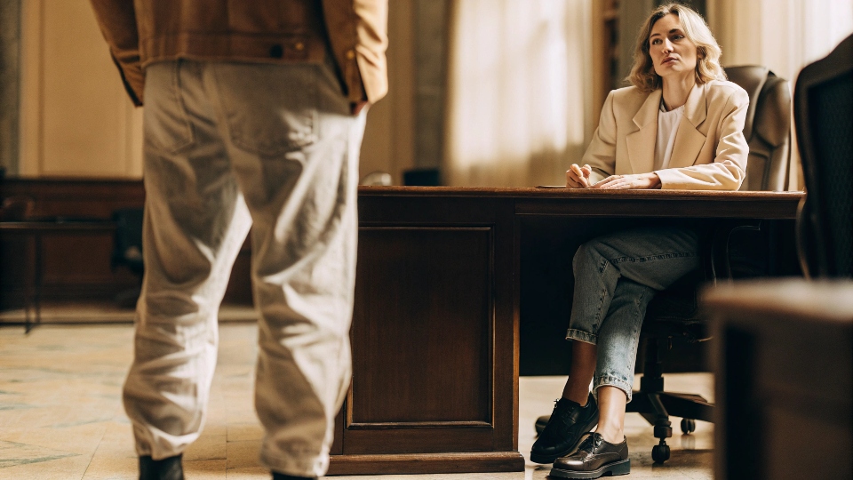A hiring manager shaking her head slightly at a candidate wearing baggy jeans to an interview.