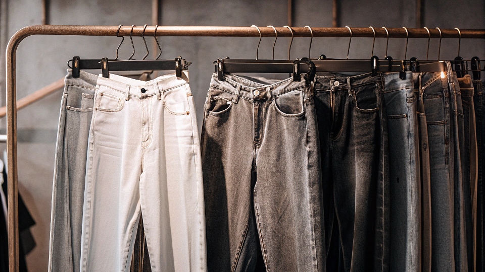 A clothing rack featuring a variety of popular jean styles: straight-leg, wide-leg, and baggy cuts.