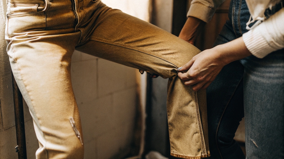 A person stretching a pair of damp jeans over their knee to widen the thigh area.