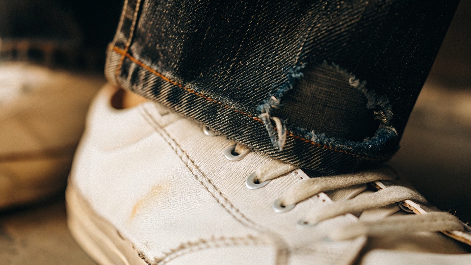 A close-up of dark denim rubbing off onto a white canvas shoe, an effect known as crocking.