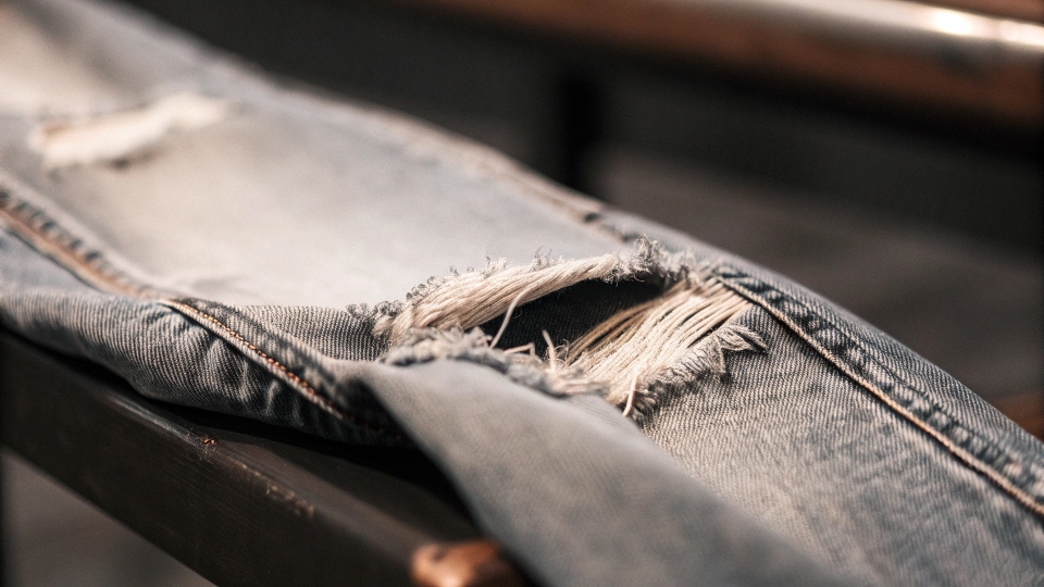 A close-up, almost microscopic view of denim fabric, showing a few broken fibers starting to fray.