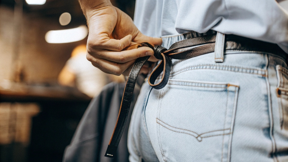 A close-up demonstration of the shoelace trick on the back of a pair of jeans.