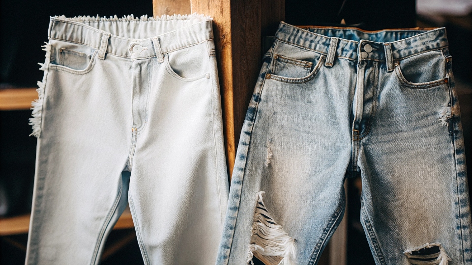 A pair of jeans with the waistband cut off, showing a trendy, raw frayed edge as a no-sew finish.