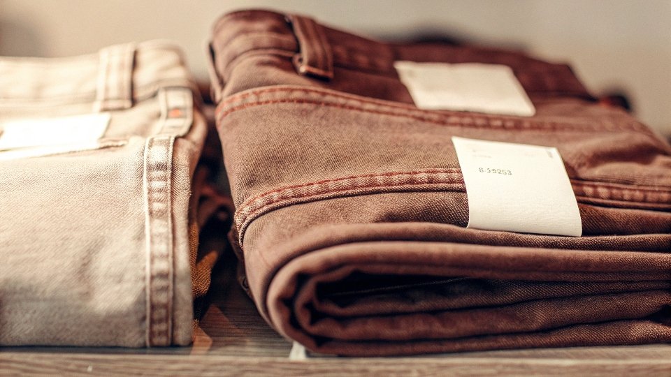 A pair of 100% cotton jeans with a care label showing cold wash instructions.