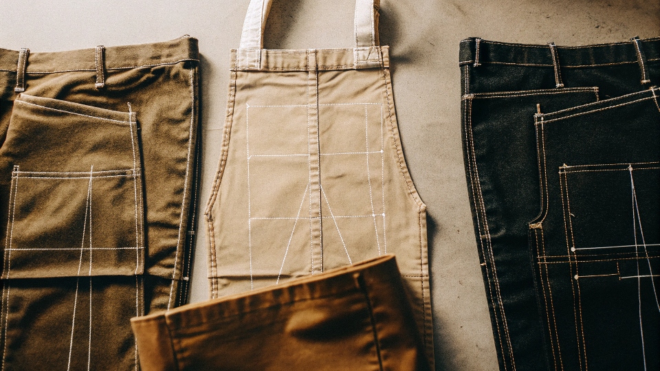 A flat lay of dismantled jeans, with chalk lines showing where to cut the front, back, and side panels for a tote bag.