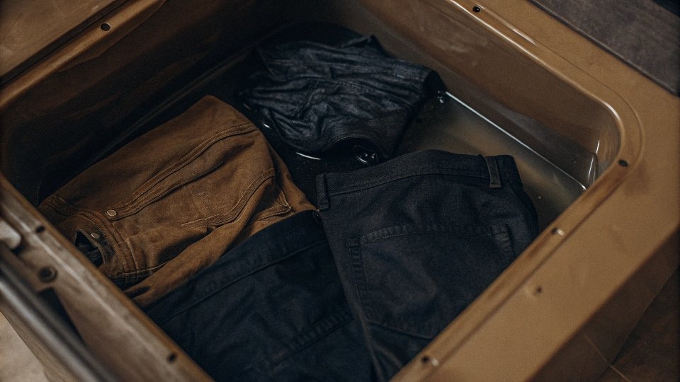 An open washing machine with a packet of black fabric dye and several faded black clothing items inside.