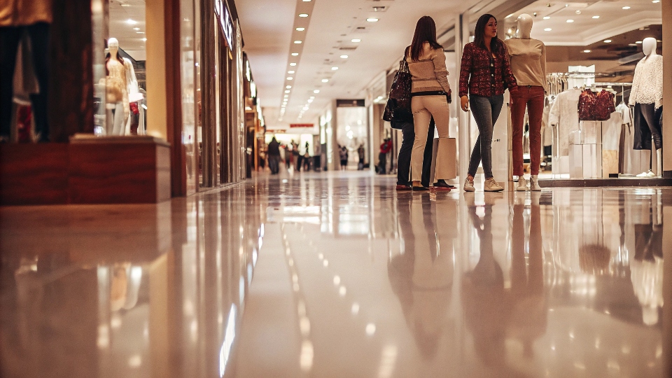 A modern, brightly lit Guess retail store in a busy shopping mall.