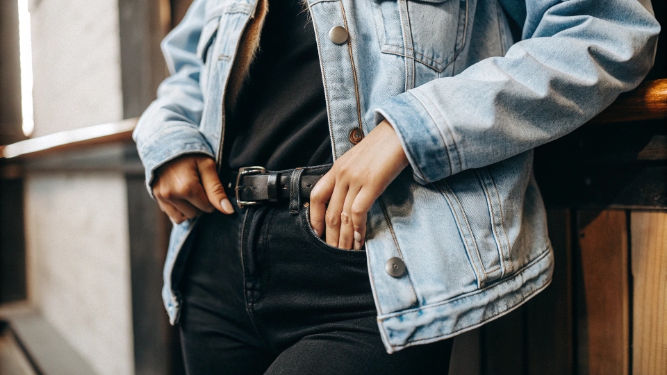 A person looking cool and well-dressed in a blue denim jacket paired with contrasting black jeans.
