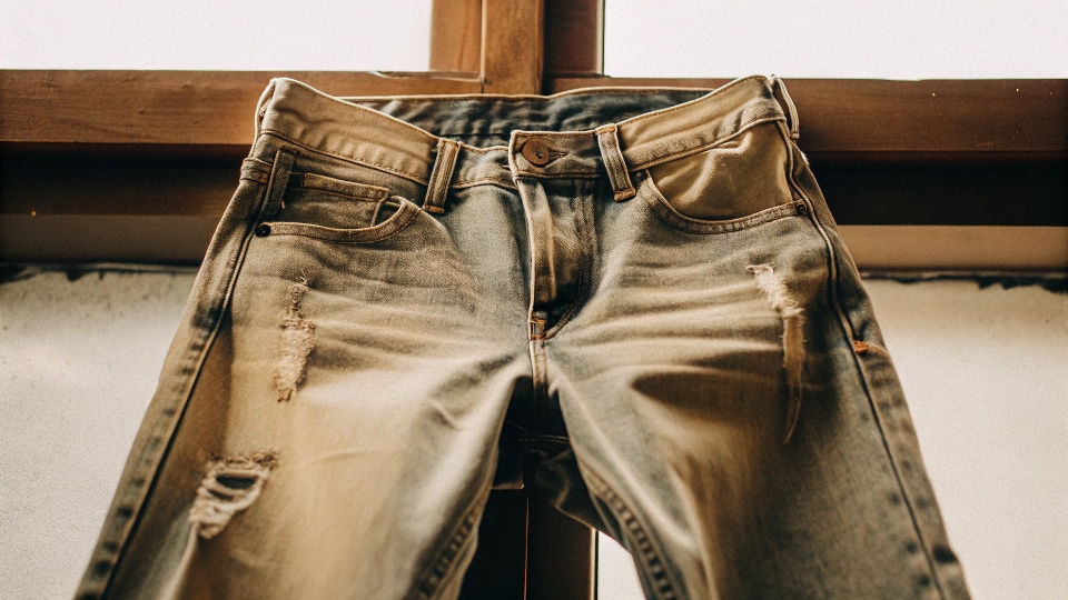 A pair of distressed jeans turned inside-out, with care instructions like 'Cold Wash' and 'Hang Dry' shown as icons.