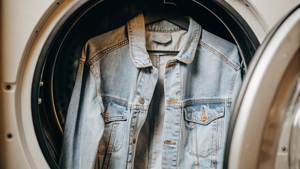 a single denim jacket spinning alone inside a washing machine